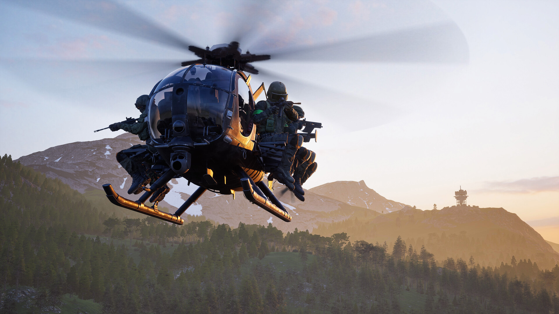WARDOGS soldiers riding a Little Bird helicopter over a forested valley at sunset